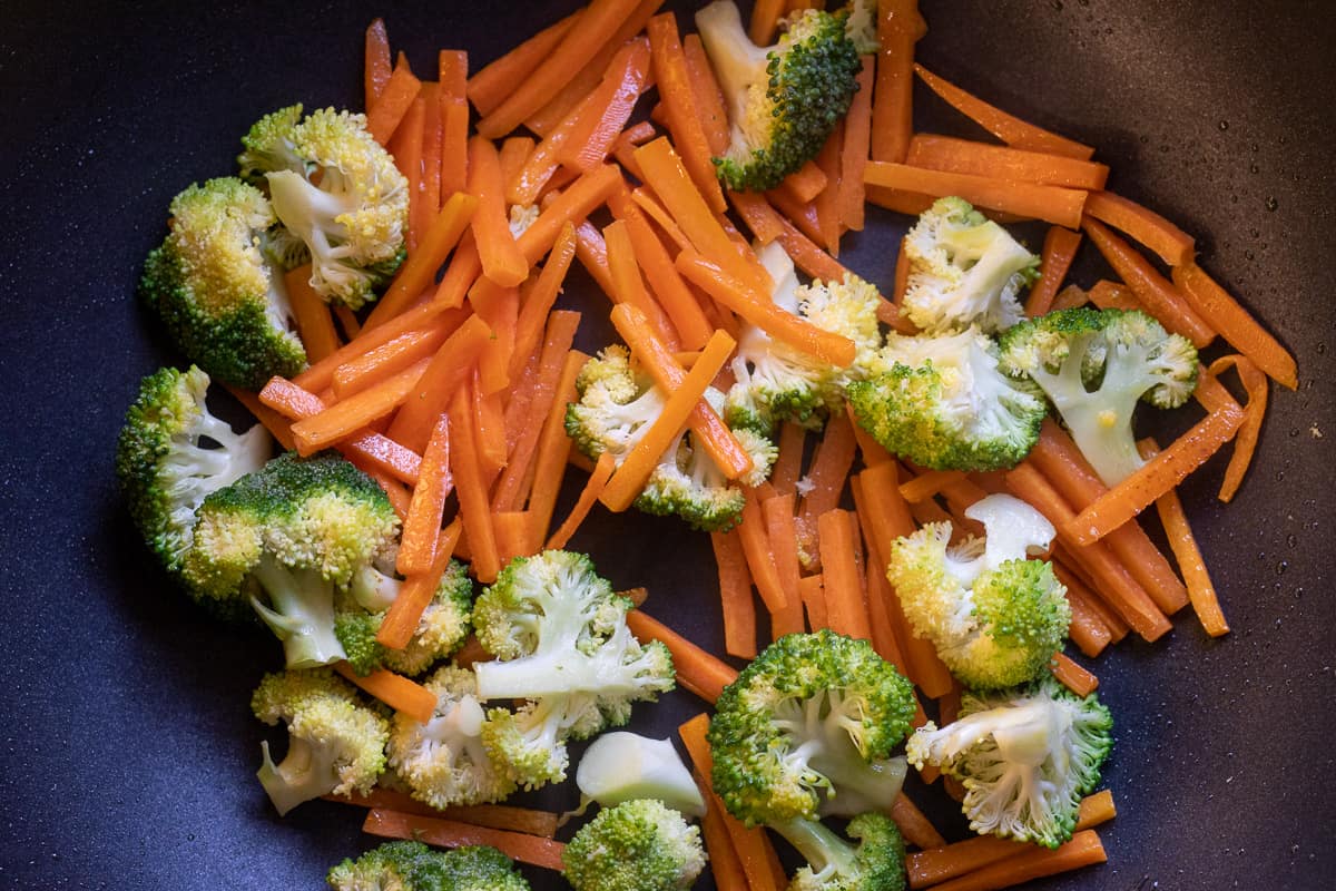 stir frying the carrots and broccoli in a wok