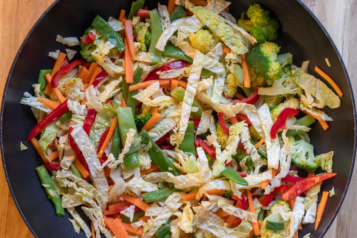 the cabbage, peppers and beans are added to the wok