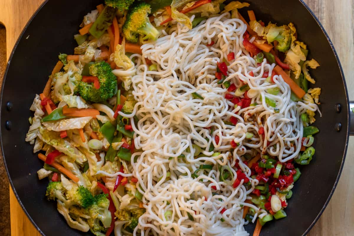 the noodles, the marinade and spring onions are added to the wok