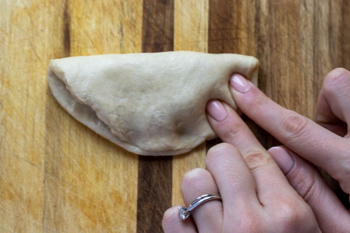 the other side of the dough is folded over the filling and gently pressed to stick to each other