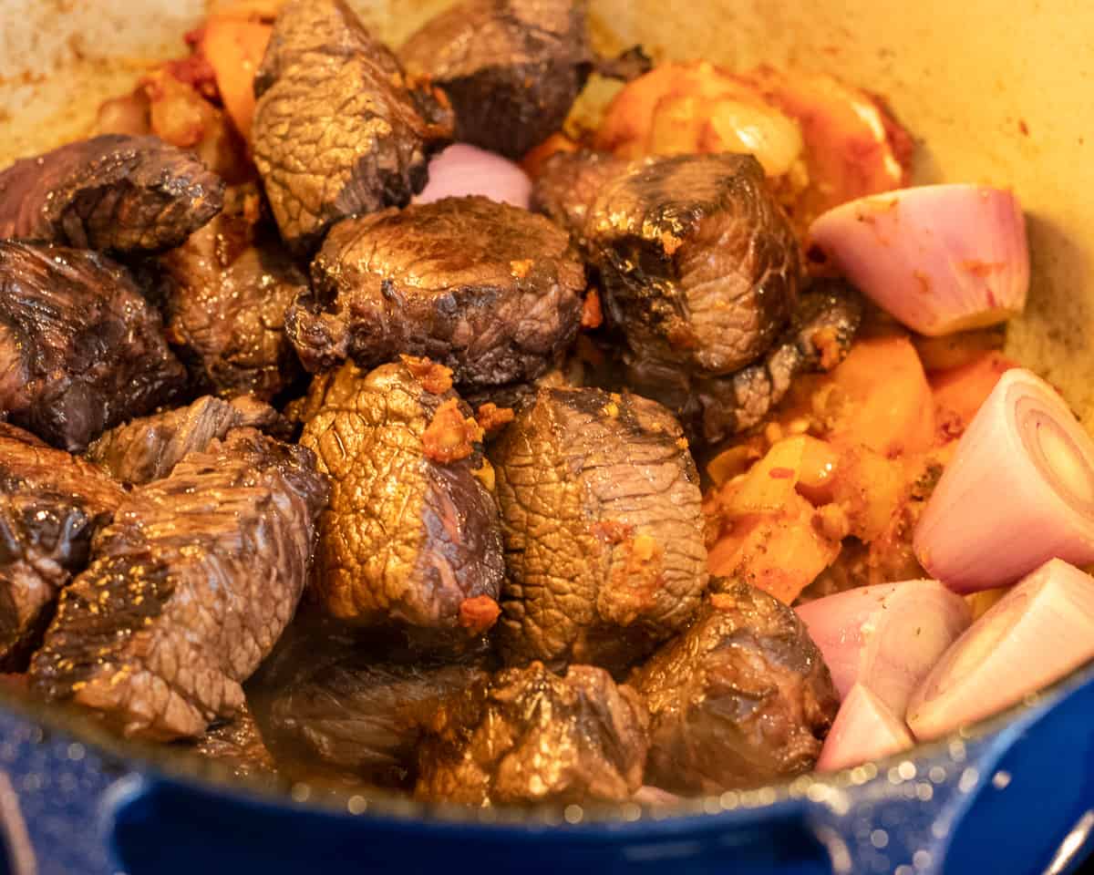 the seared beef and button onions are added to the pan