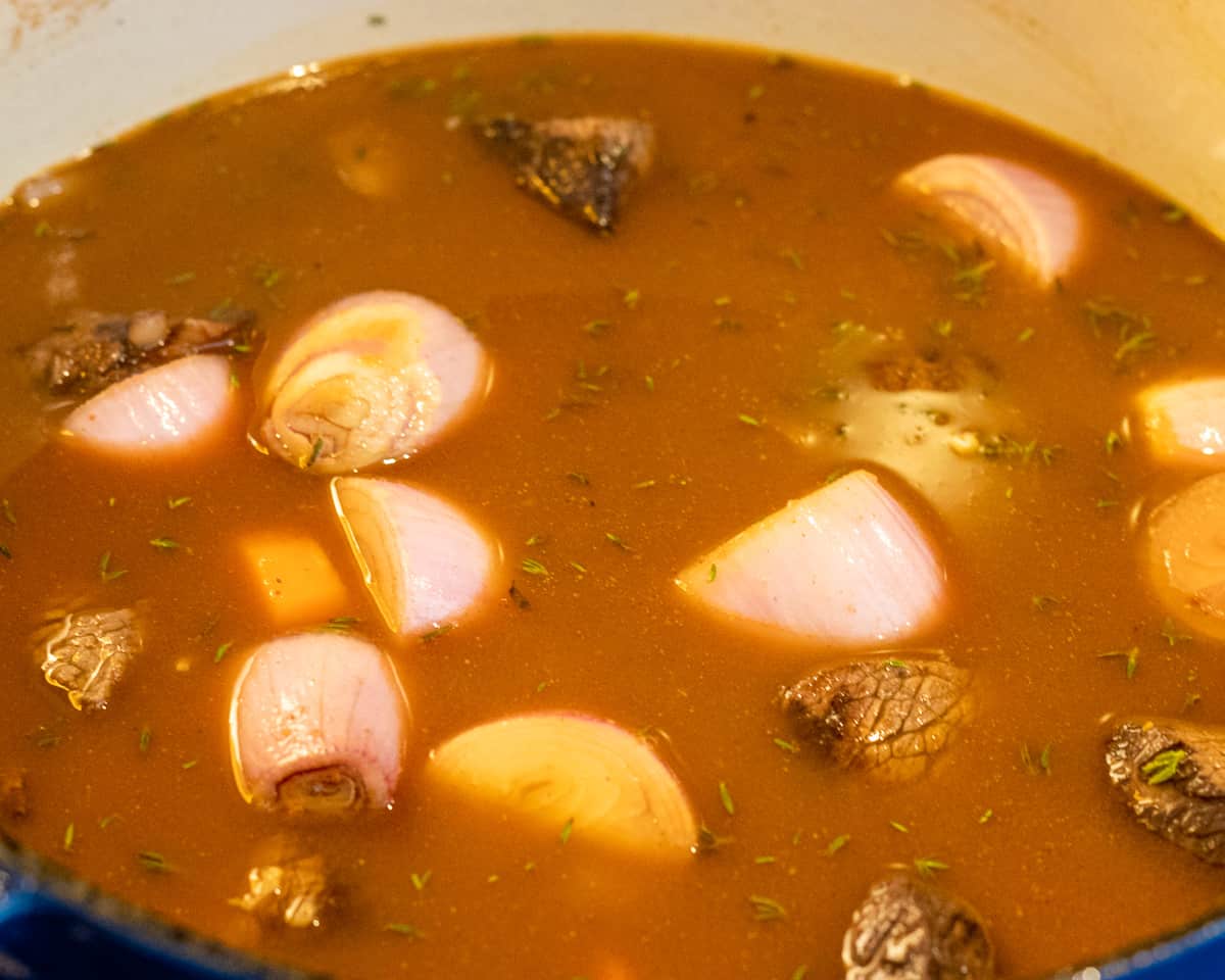 Wine from the marinade and the beef stock is added to the pan