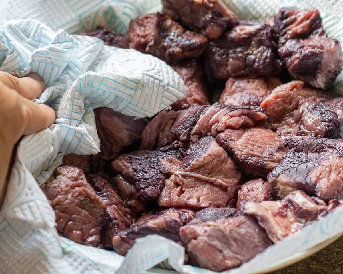 pat drying the beef pieces that are marinated in burgundy wine