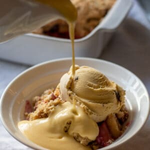 pouring custard over a bowl of apple crisp without oats