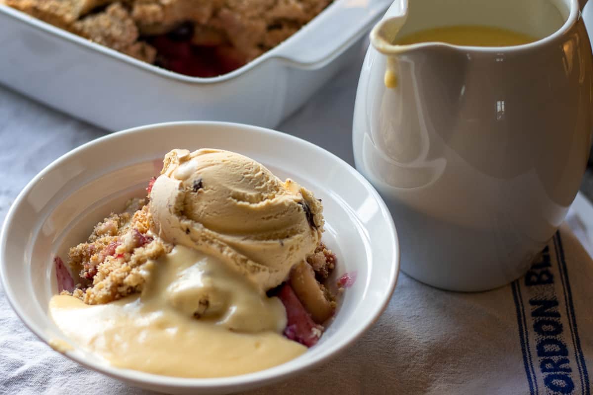 a bowl of apple crisp served with custard and ice cream