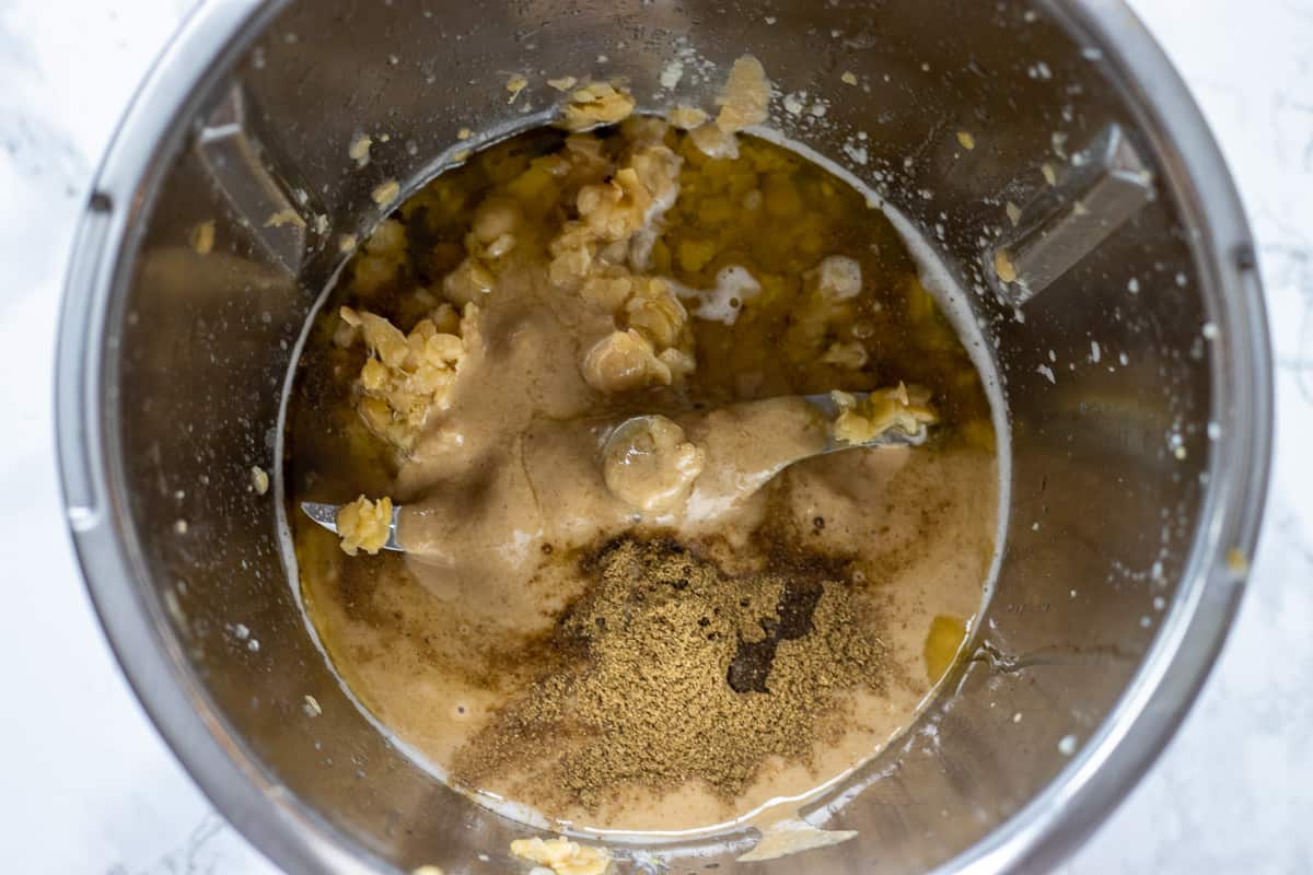 The tahini, chickpeas and spices are added to lemon and garlic