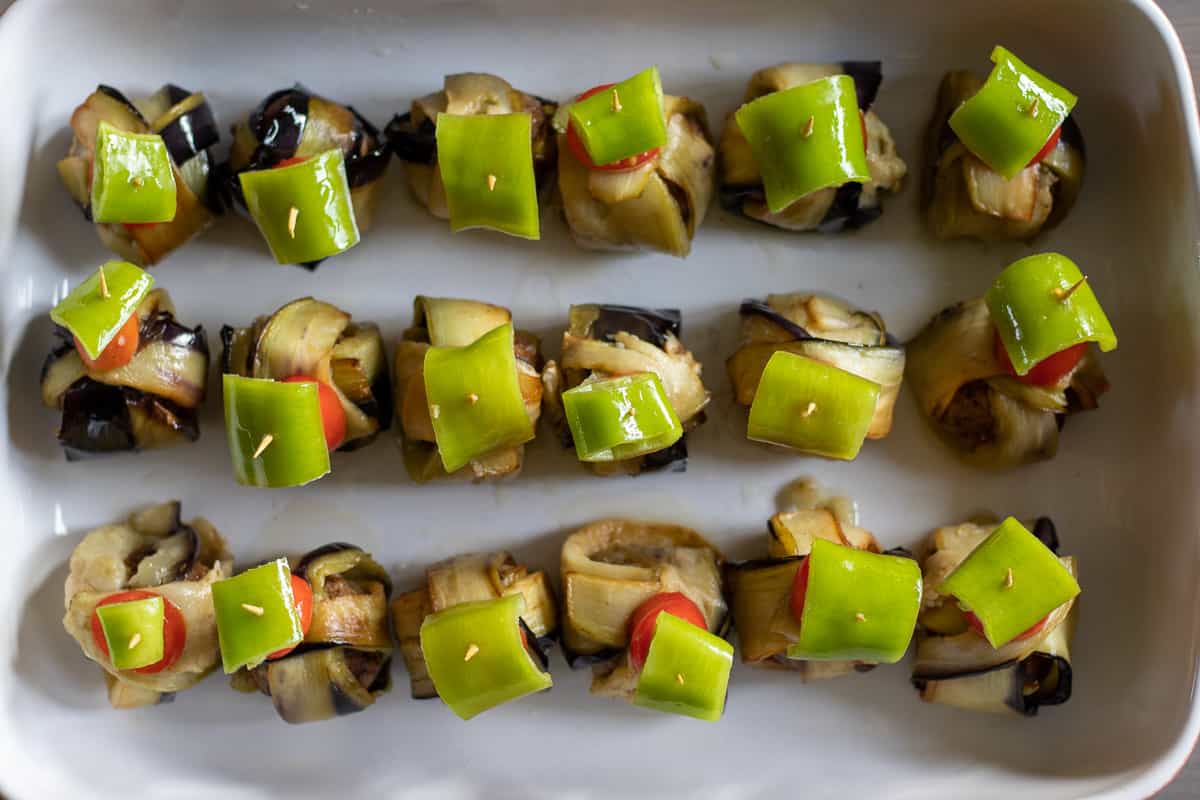 aubergine meatball wraps are arranged on a baking dish