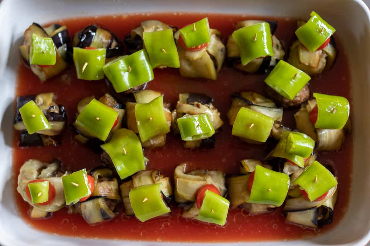aubergine wraps are placed in an oven dish with tomato sauce