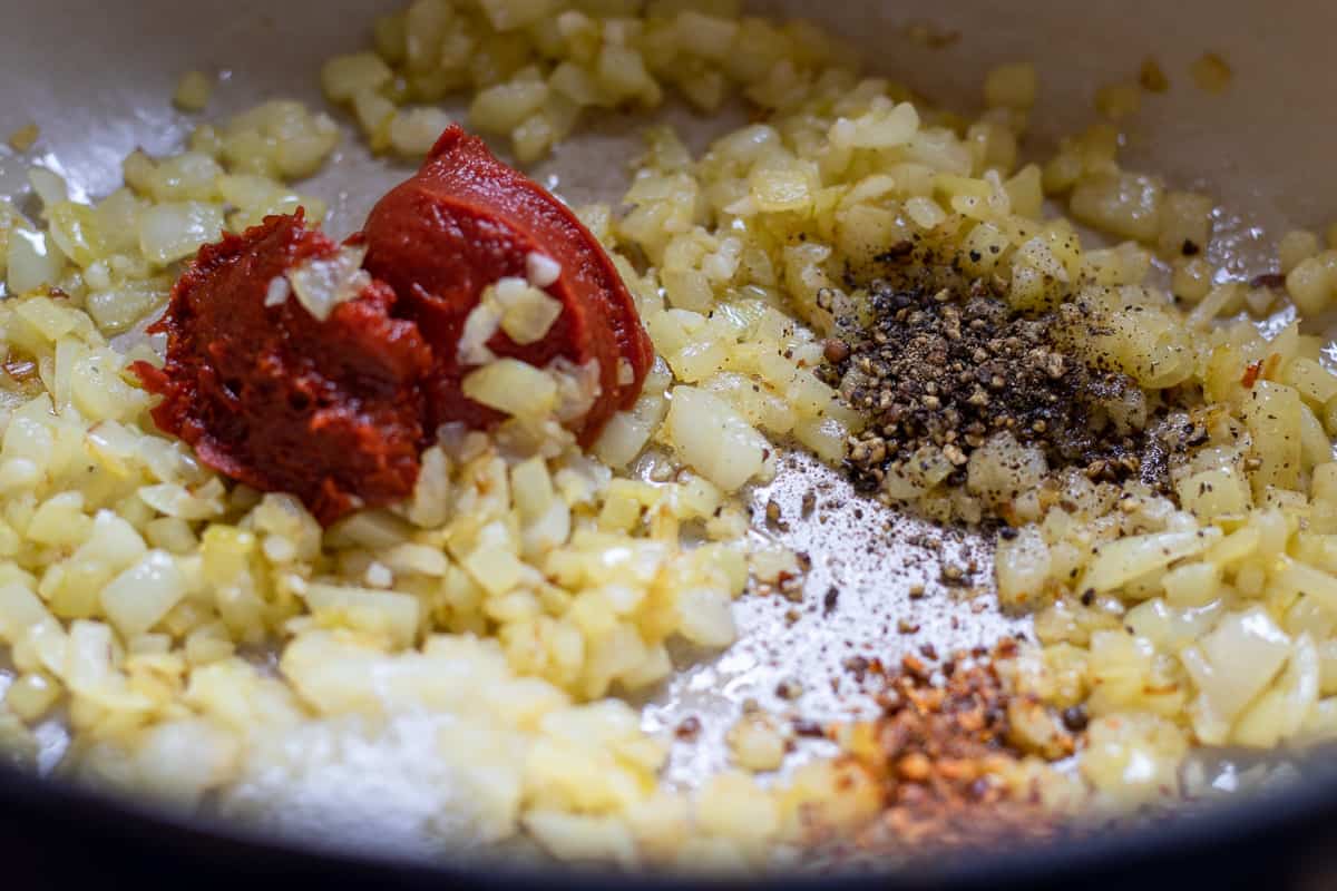 The tomato paste and spices are added to sautéed onions