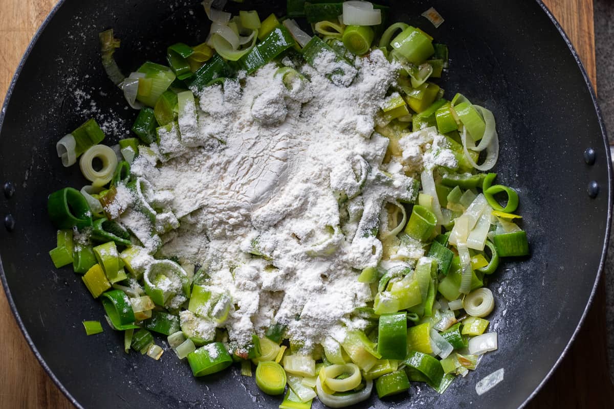 flour is sprinkled on top of sautéed leeks