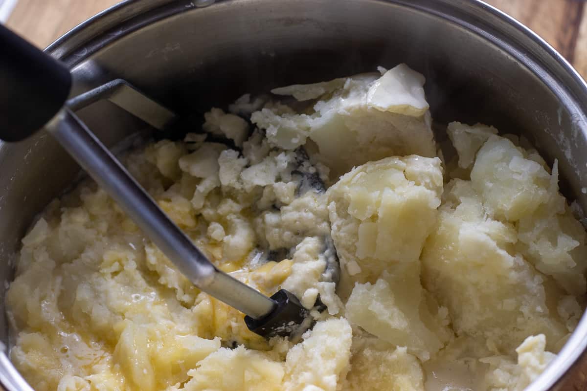 mashing the potatoes with a masher