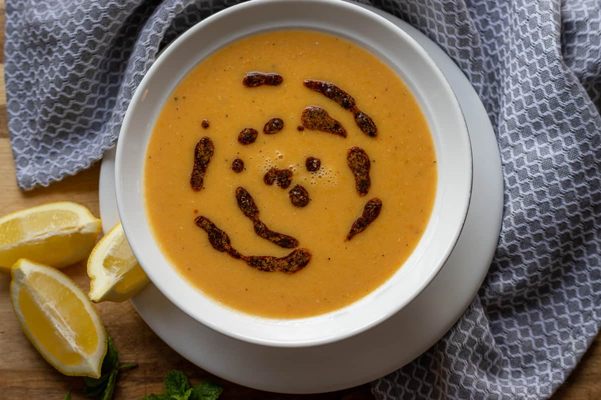 Turkish red lentil soup garnished with chili oil and served with lemon