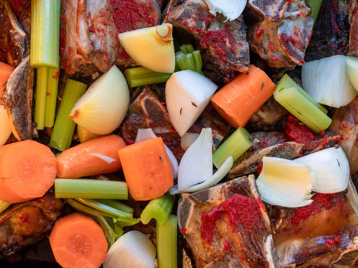 tomato paste and mirepoix are added to the roasted bones