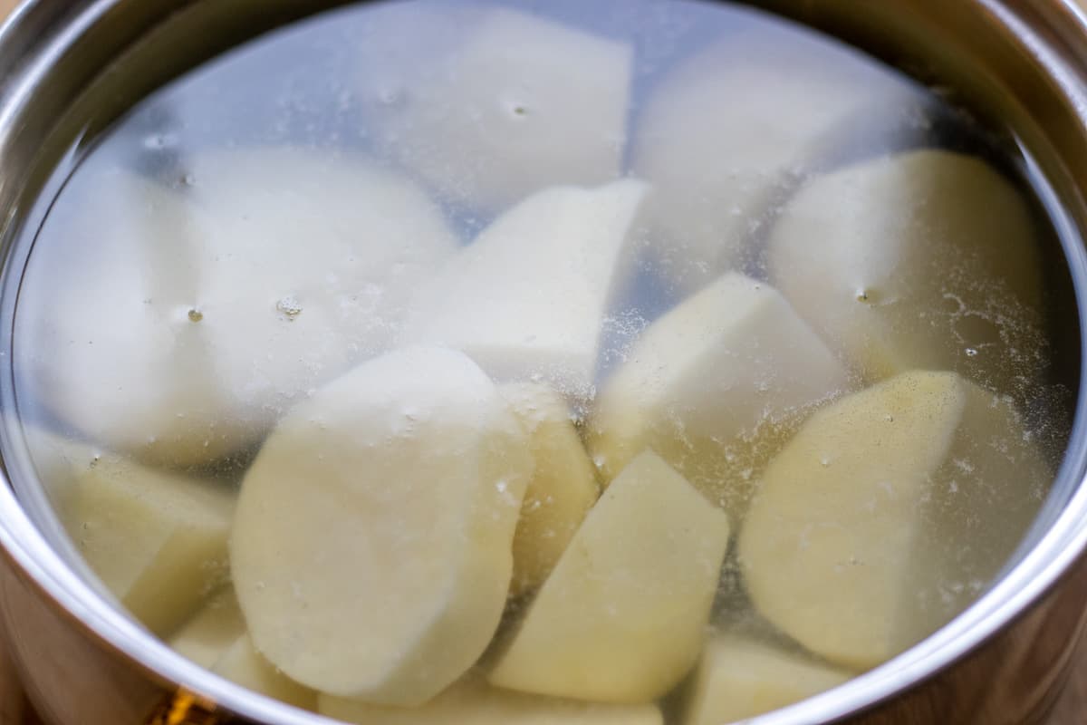 the potatoes are peeled, cut in chunks and placed in a pan with cold water
