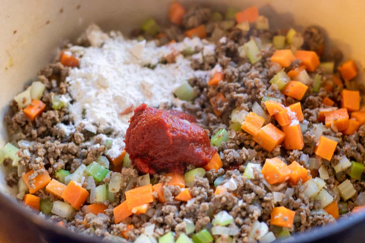 the flour and tomato paste are added to the meat