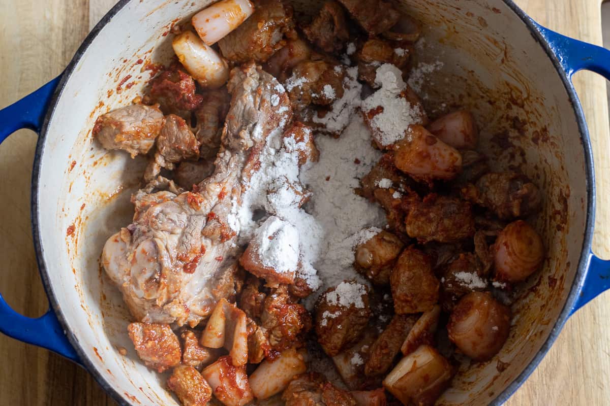 tomato paste and flour are stirred in the dutch oven