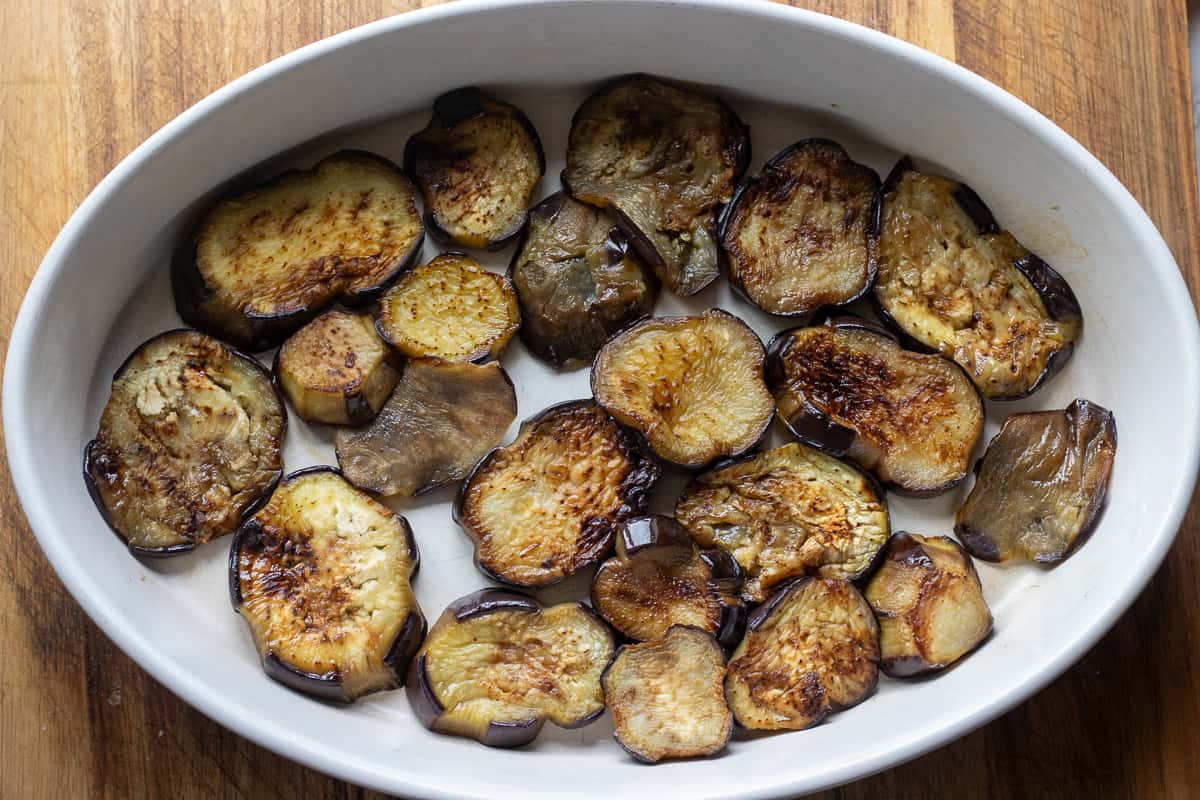 half of the eggplants are layered to a bottom of a baking dish