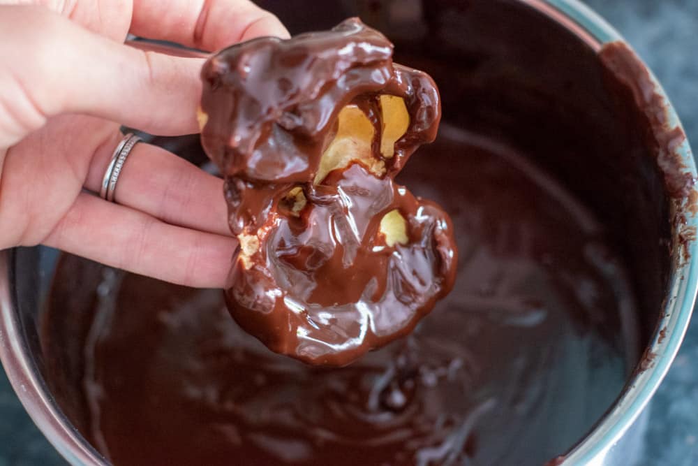 choux pastry is dipped in chocolate ganache