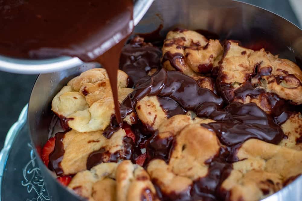 pouring the chocolate ganache on choux pastries