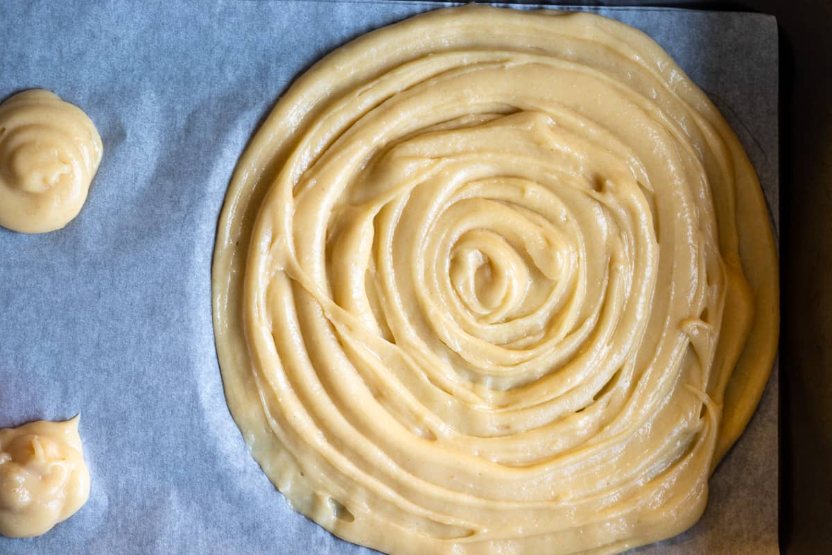 choux pastry dough is piped on a tray