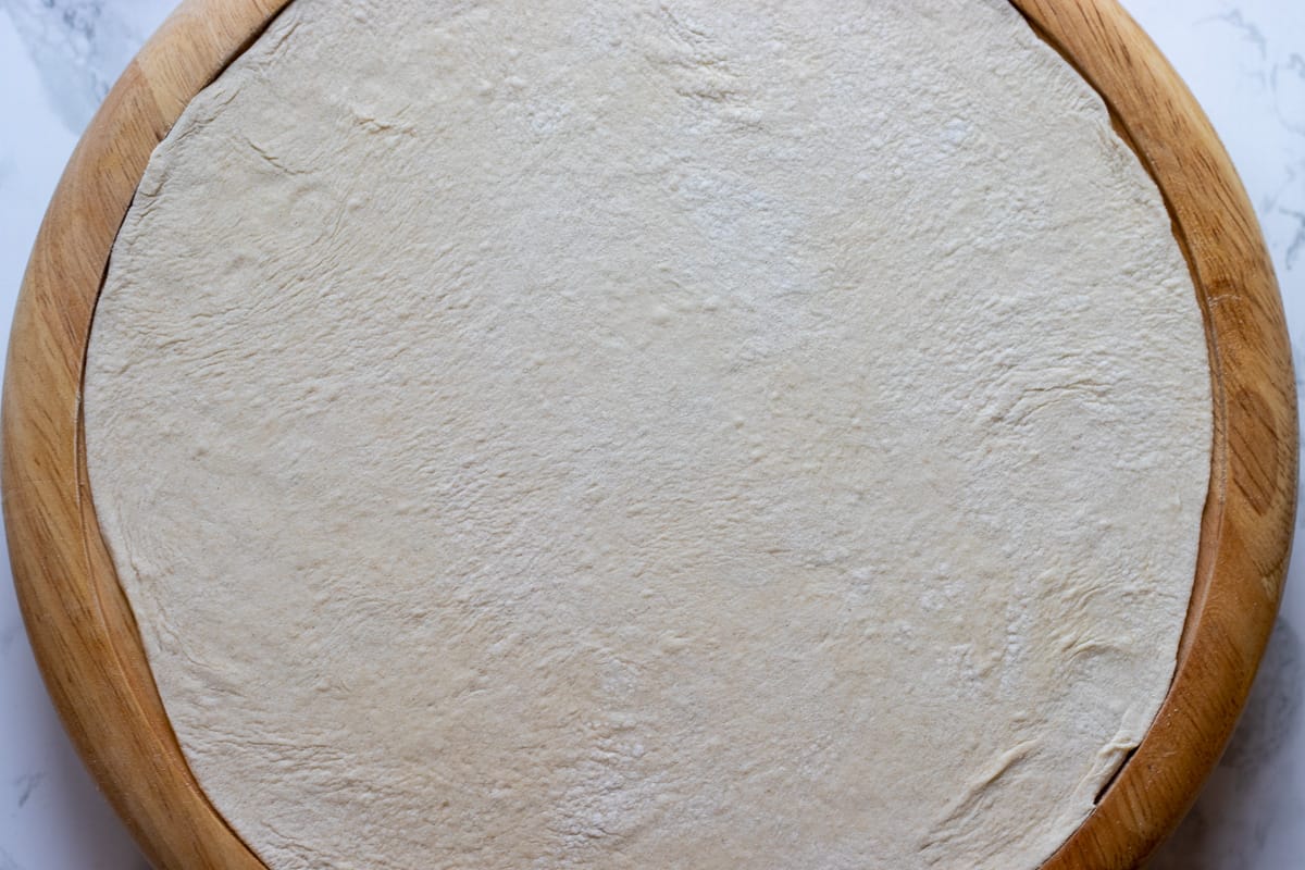 one of the dough balls is rolled out into a circle