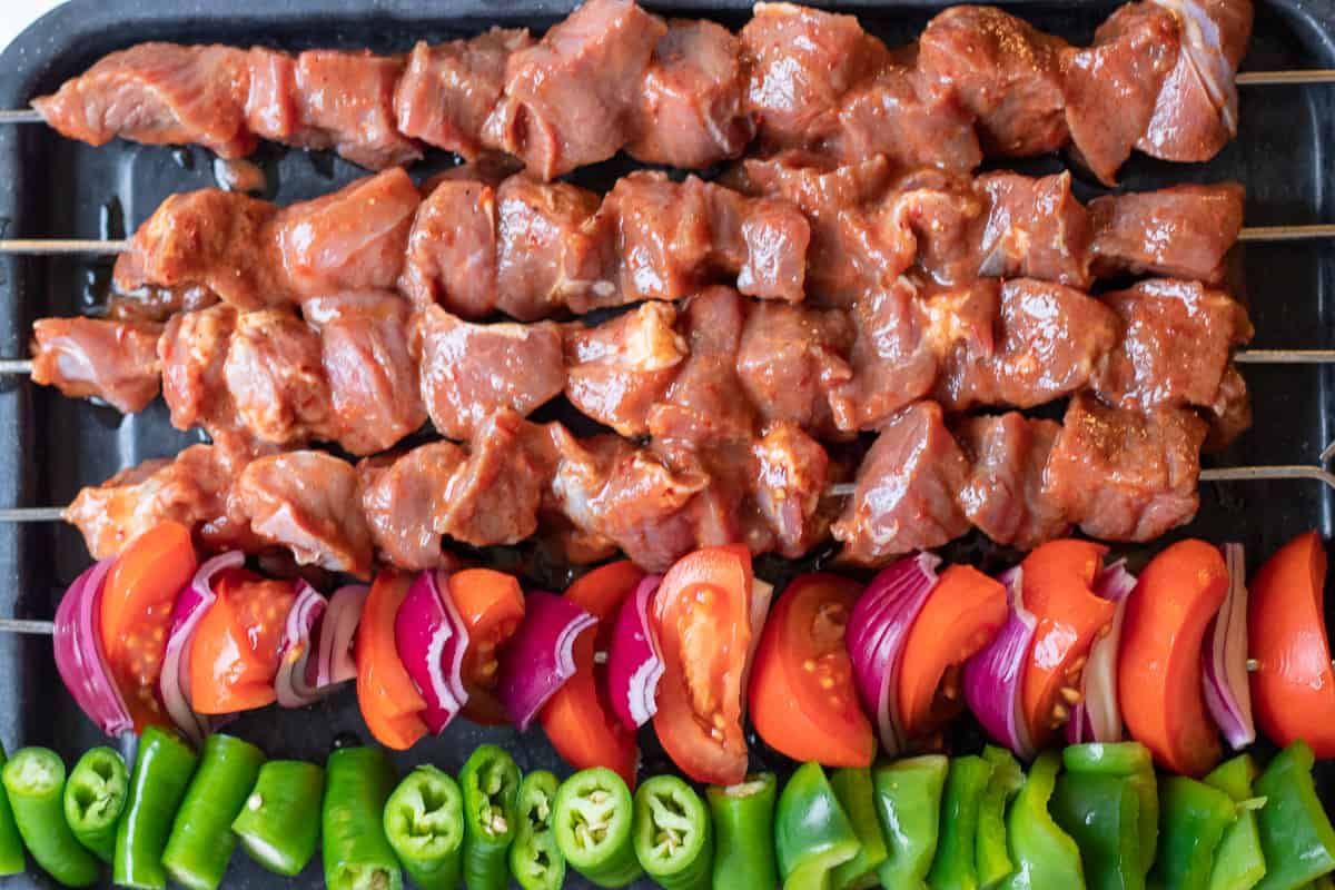 The lamb and vegetables are threaded on metal skewers separately