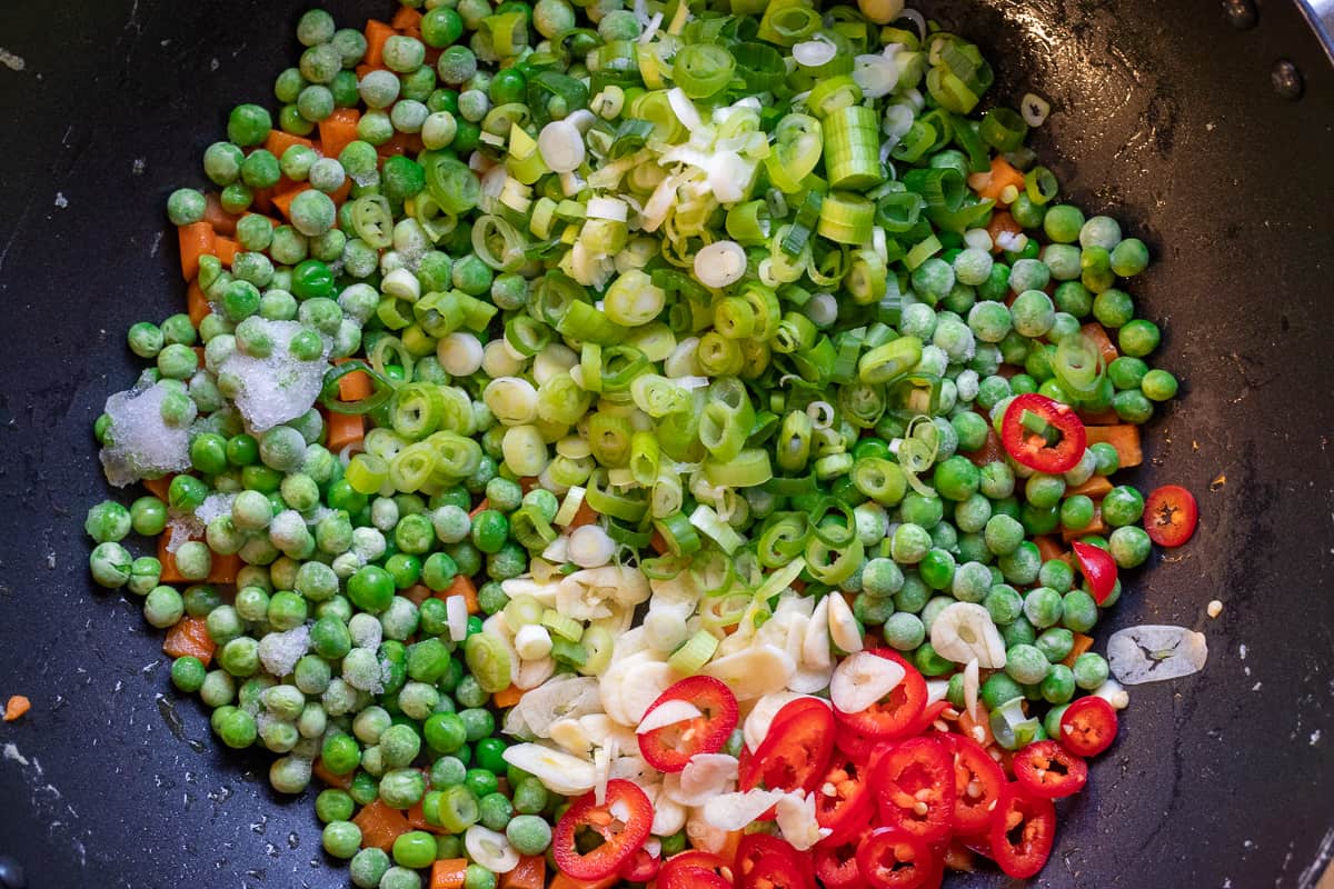 the peas, garlic, chillies and spring onions are added to carrots