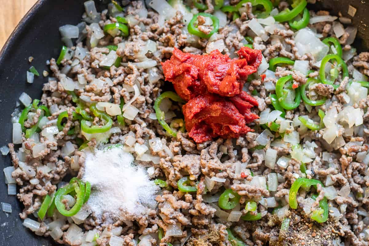 tomato paste and seasoning are added to the pan