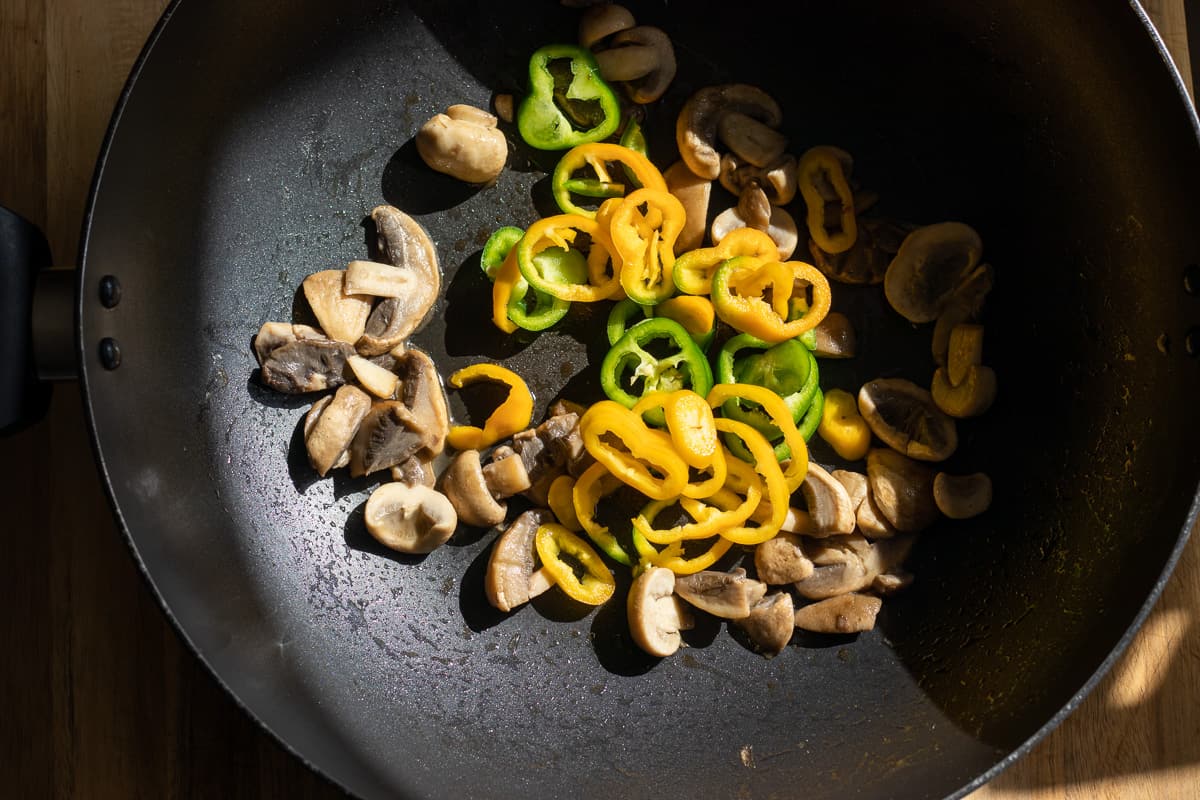 Sautéing ethe peppers with mushrooms