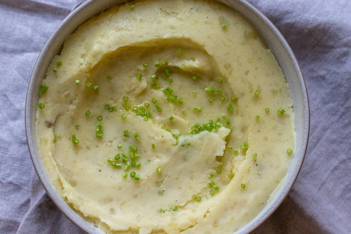 a bowl of mashed potatoes garnished with fresh herbs