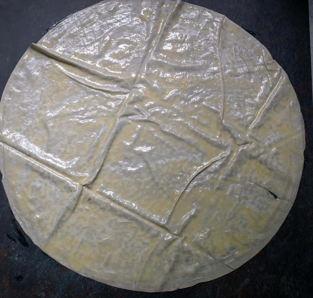 Apiece of yufka is laid on a work surface and scattered with 2-3 tablespoon of the sauce