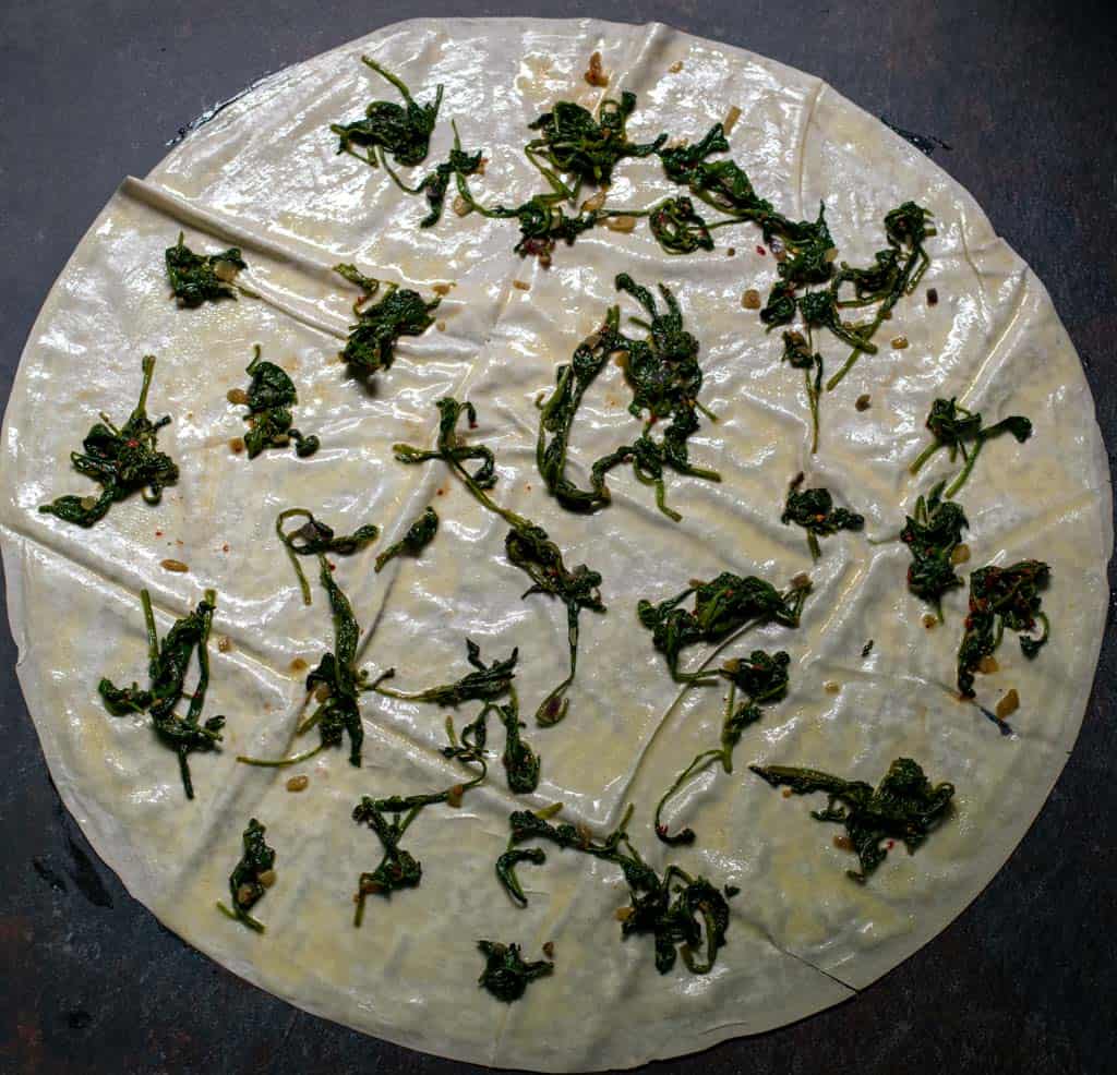 The filling is divided into 3 and ⅓ of it is scattered on yufka evenly.