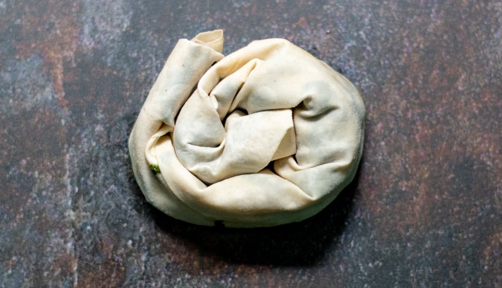 the loose end piece is tucked underneath the rose.