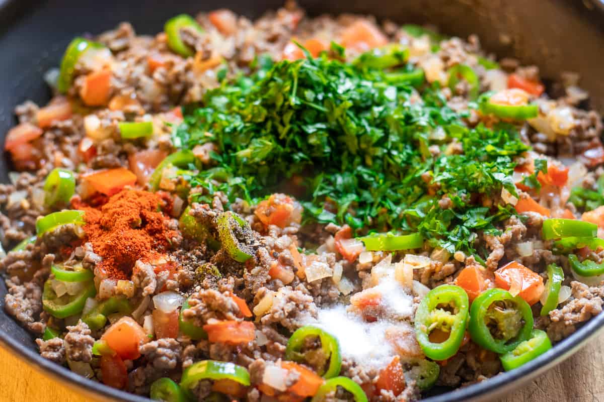 Tomatoes, spices and parsley are added to the minced beef pie mixture