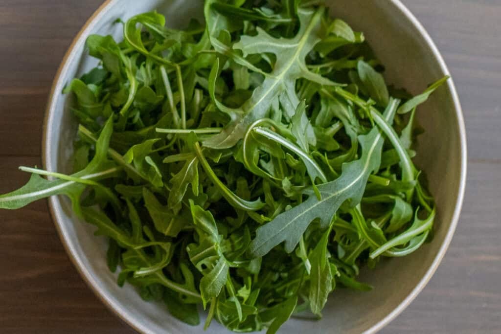 Washed and dried arugula leaves in a bowl.