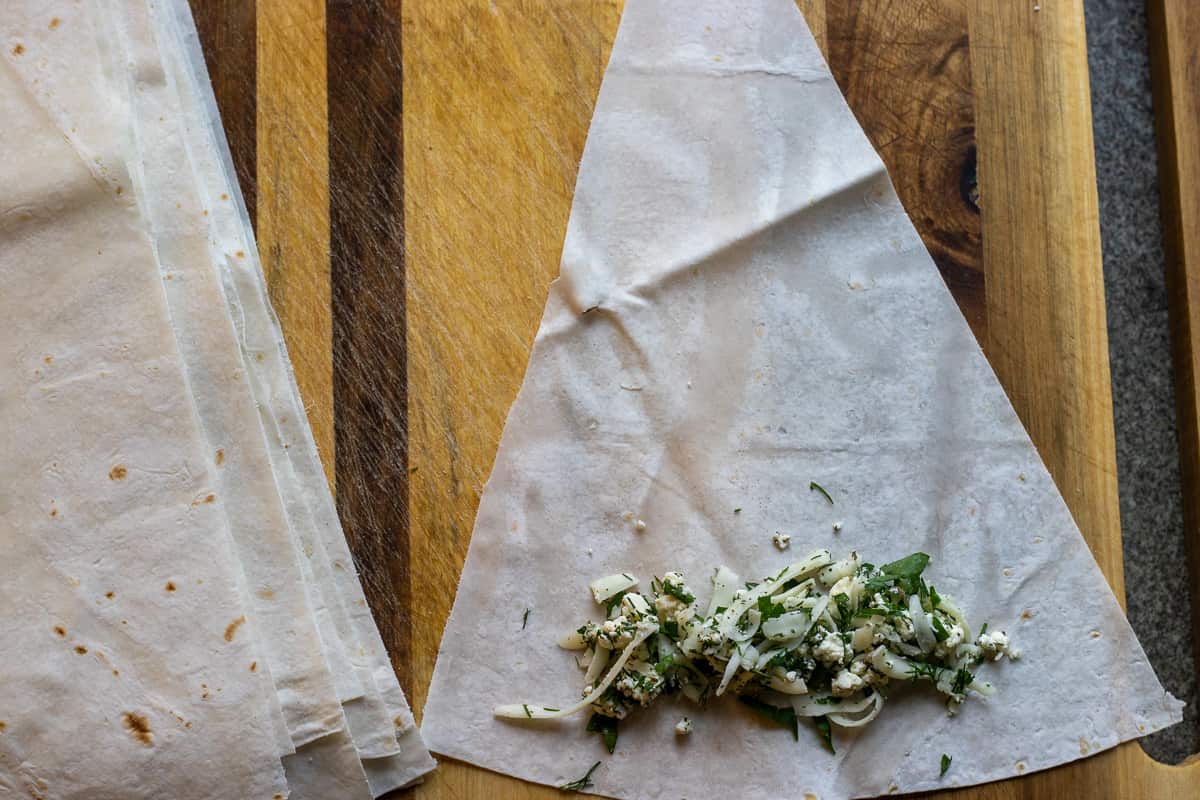 a spoonful of filling is placed on the long side of the triangle