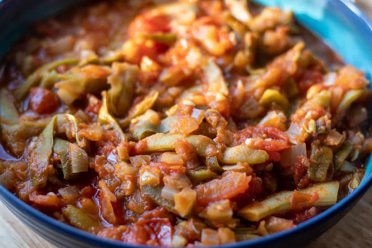 turkish green beans are braised until soft and served at room temperature in a bowl