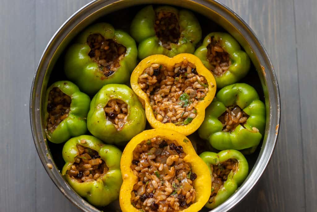 Bell peppers are stuffed with rice filling and placed in a pot.