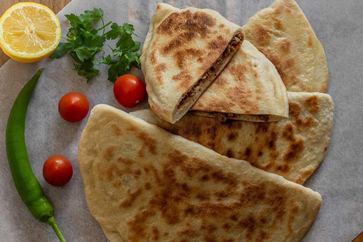 4 pieces of gozleme served with tomatoes, peppers and parsley 