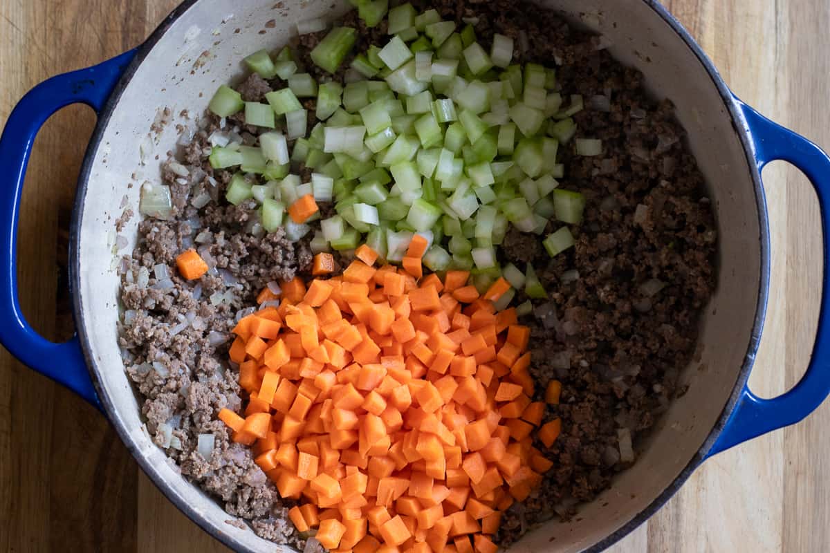 Diced carrots and celery are added to sauteed meat.