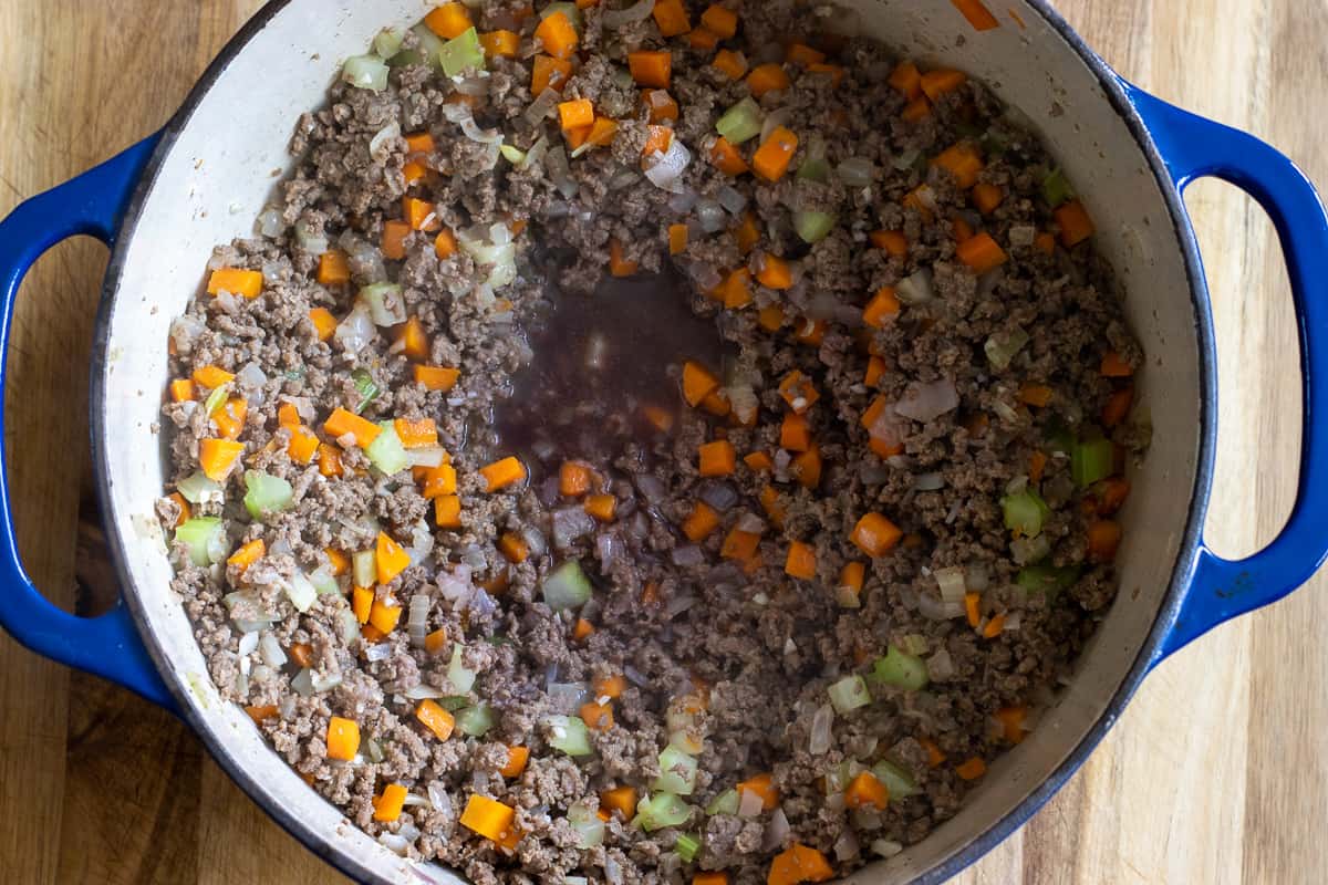 Deglazing the bottom of the Dutch oven with red wine.