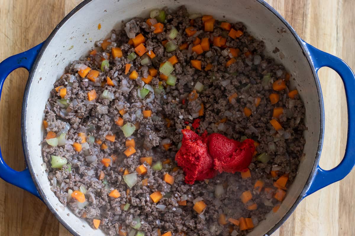 The tomato paste is added to the pan.