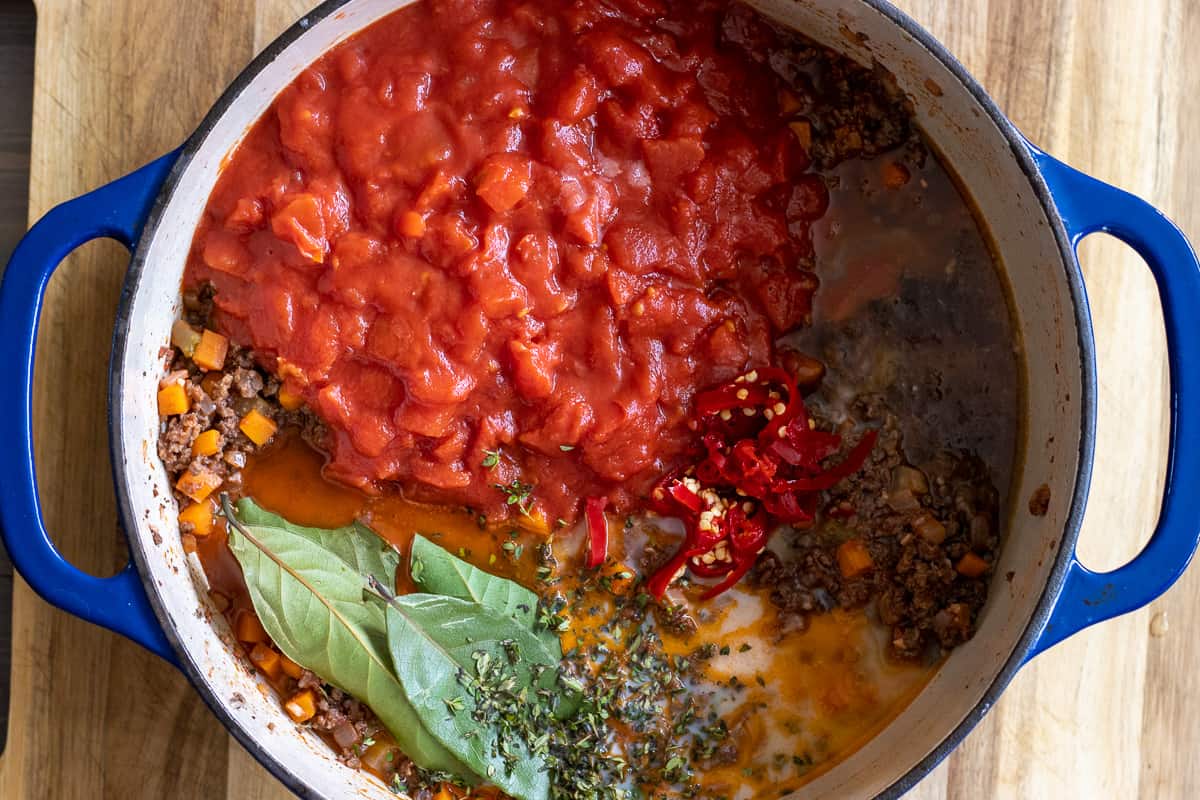 Chopped tomatoes, bay leaves, stock, milk and seasoning are added to the pan.