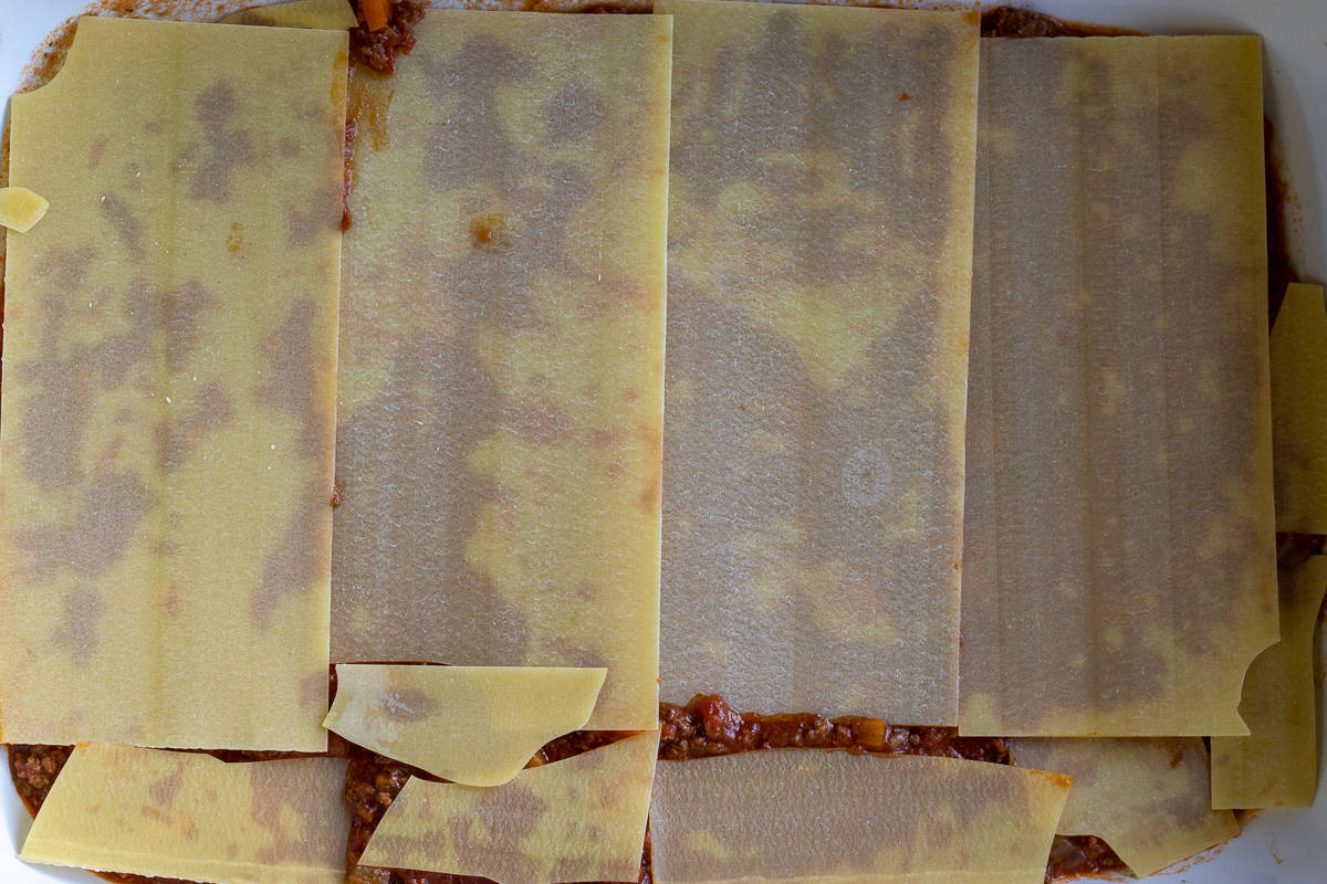 Lasagne sheets are layered on meat sauce.