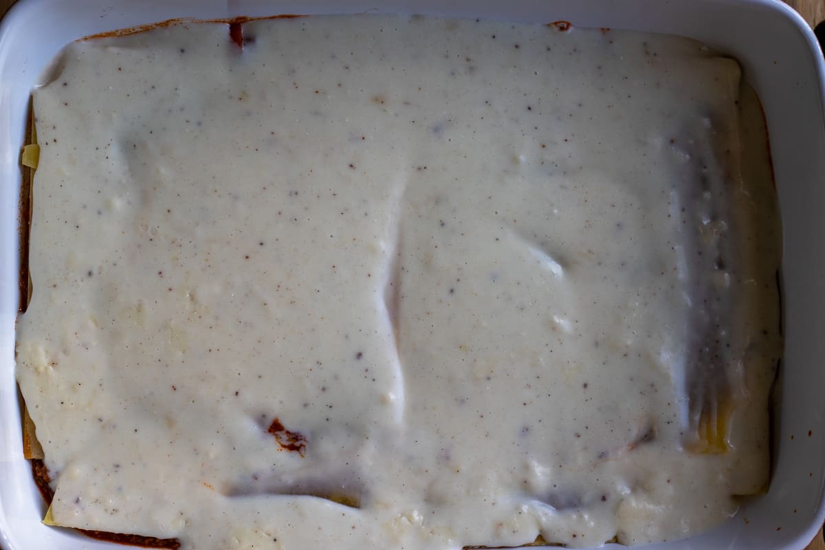 Bechamel sauce is spread on lasagna sheets.