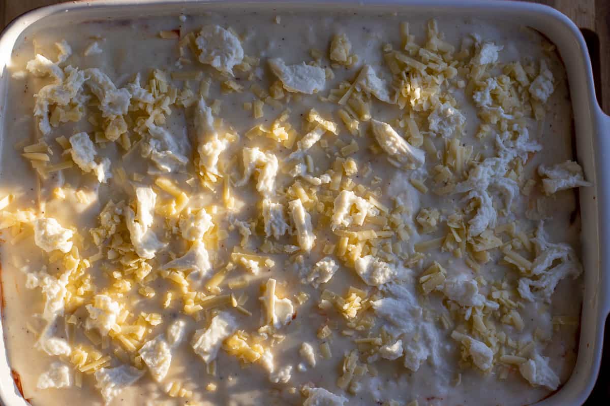 Lasagna is topped with cshredded heese before baking.