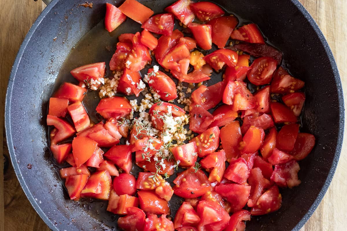 chopped tomatoes, garlic and thyme is placed in a pan with oil