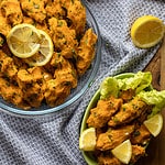 A bowl of lentil meatballs with lemon wedges