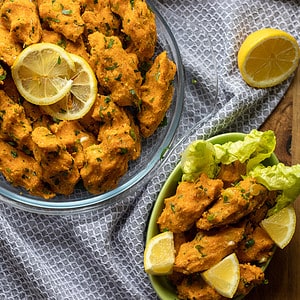 A bowl of lentil meatballs with lemon wedges