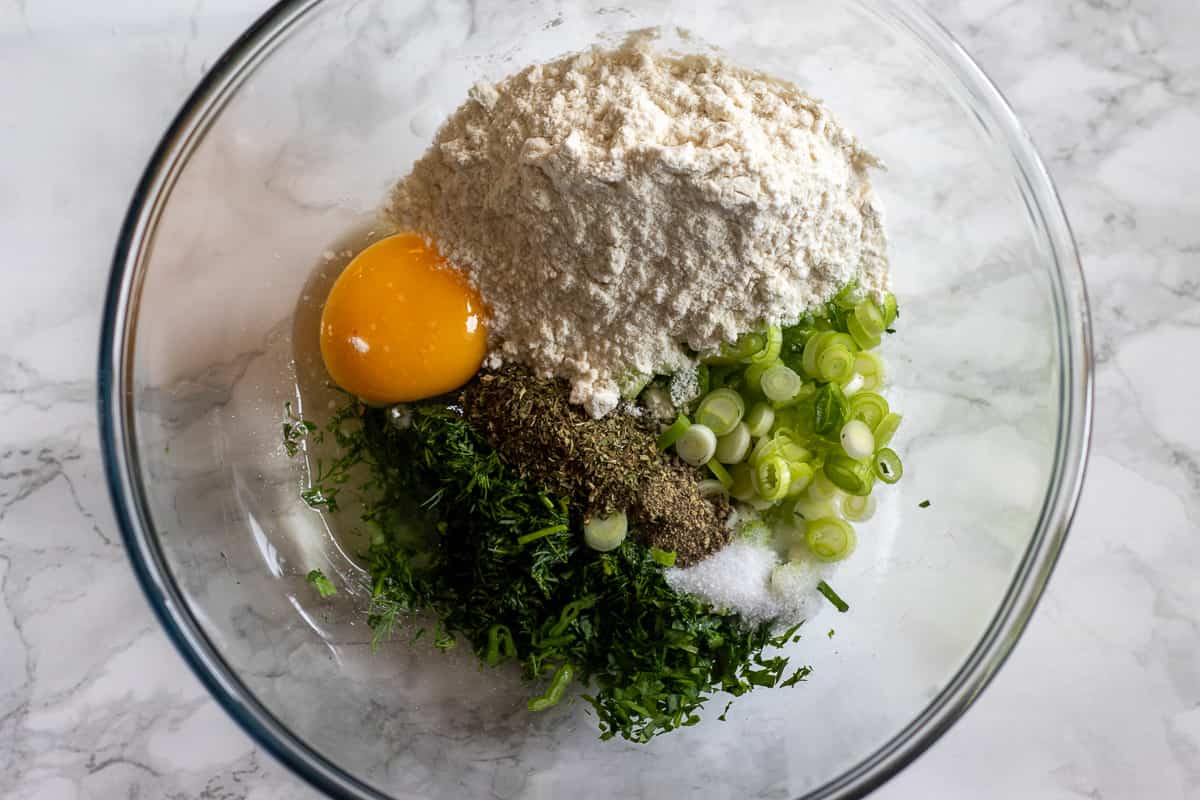 flour, egg, seasoning, spring onions and chopped herbs are placed in a bowl